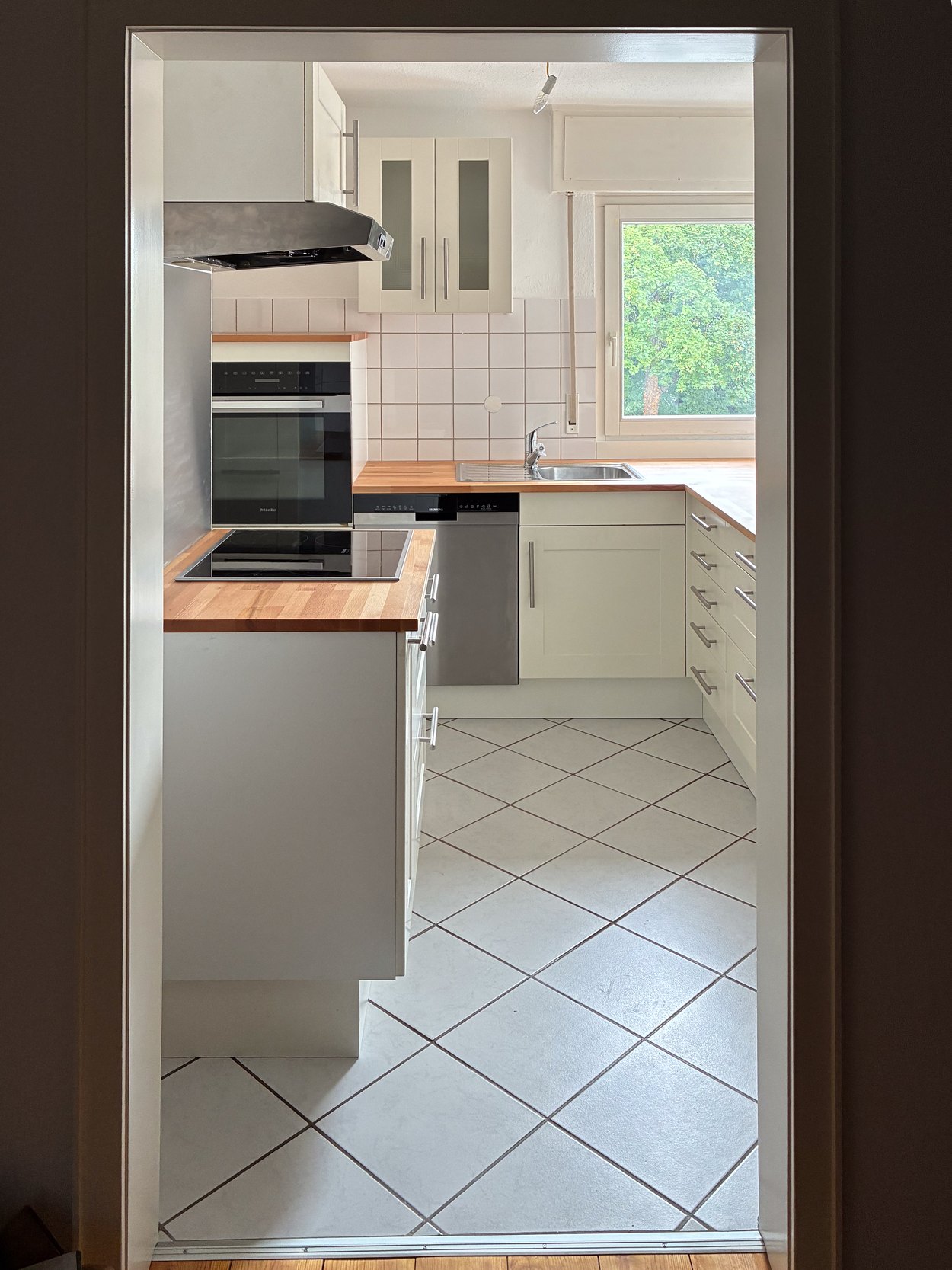 Blick durch eine Tür in eine fertig montierte helle Küche