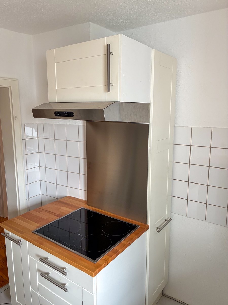 Kochfeld mit Dunstabzug und Hochschrank in einer hellen Küche